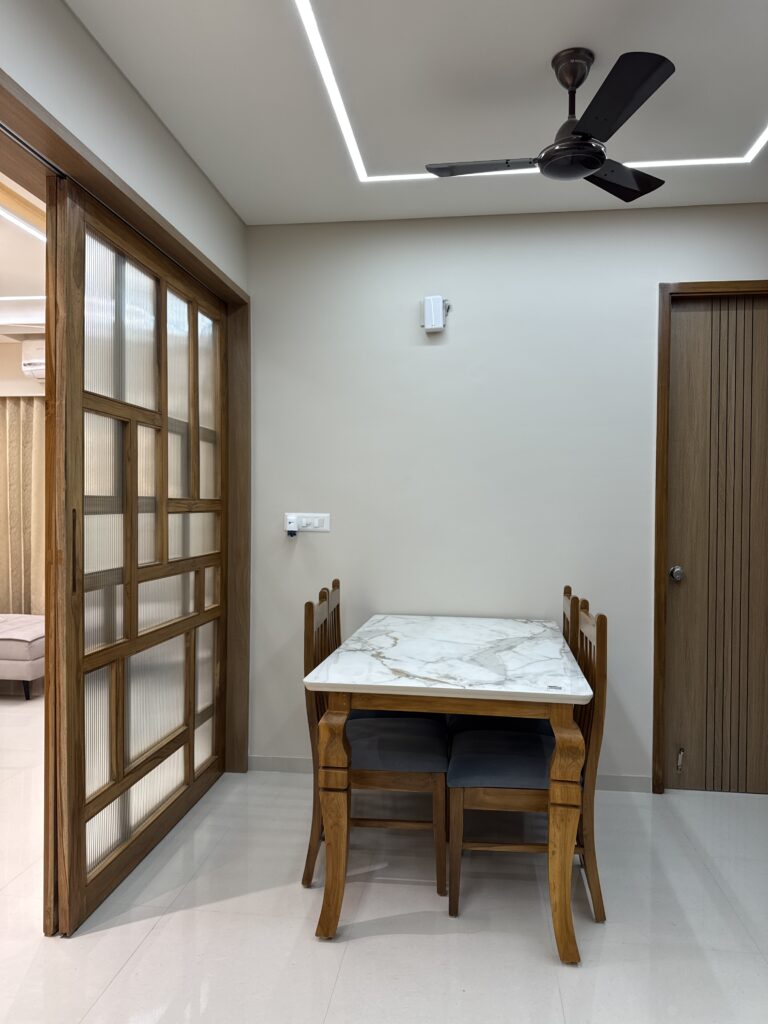 A contemporary dining room design, highlighting the contrast between the cool marble tabletop and the rich wooden dining set, enhanced by a decorative wall partition.