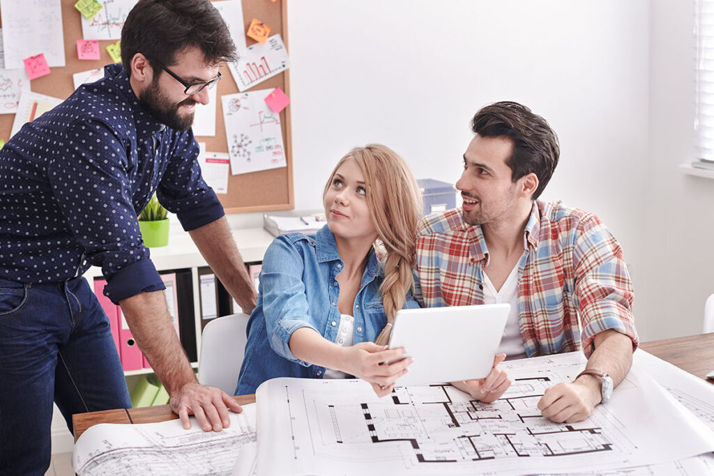 An interior designer consulting with a couple, reviewing architectural plans and design concepts on a tablet, demonstrating project management and architectural consultation