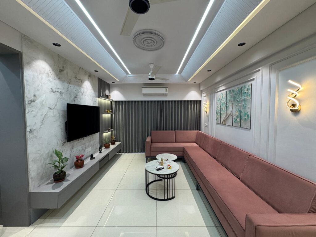 Modern living room interior design in Ahmedabad with elegant lighting and pink L-shaped sofa