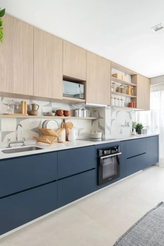Modern modular kitchen with navy blue lower cabinets and light wood upper storage, featuring open shelves and a white countertop
