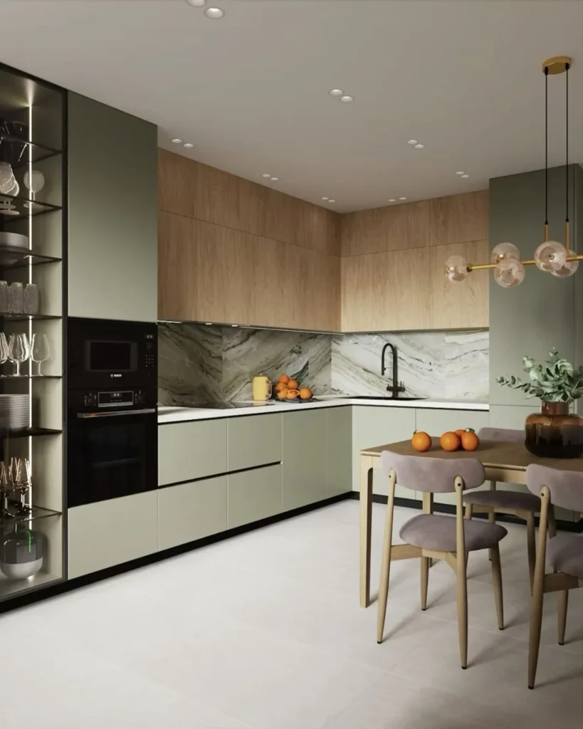 Modern modular kitchen with olive green lower cabinets, light wood upper cabinets, and a marble backsplash with a dining table
