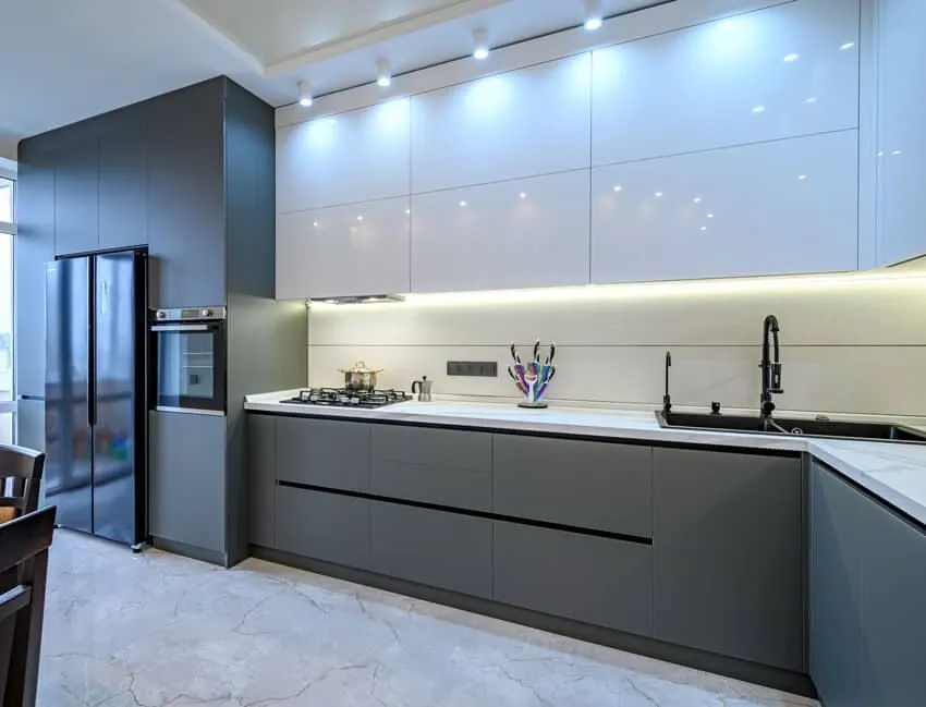 Modern modular kitchen with grey lower cabinets, glossy white upper cabinets, built-in appliances, and under-cabinet lighting