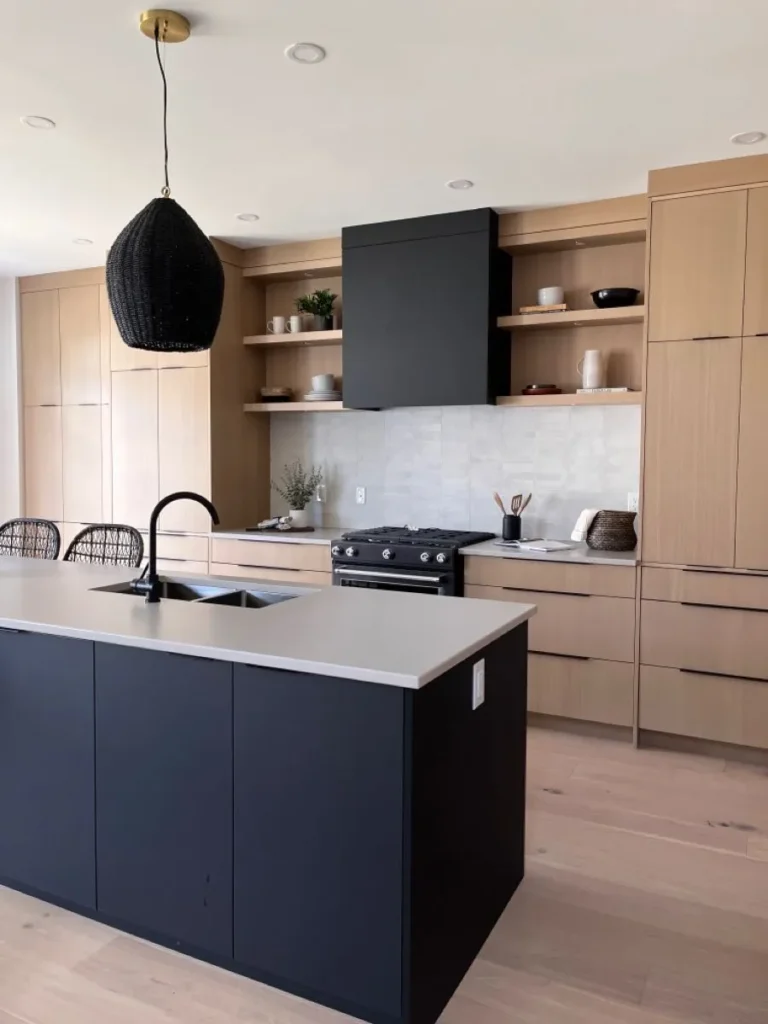 Modern kitchen with matte black island, light wood cabinets, open shelves, and a minimalist pendant light
