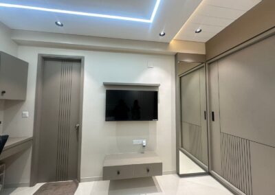 TV wall design with lower storage unit, clean panel finish, and modern ceiling lighting