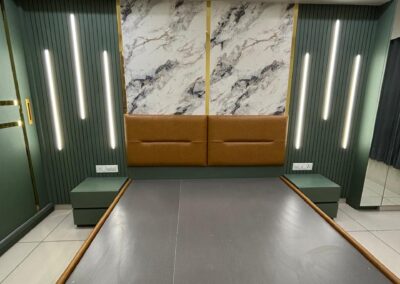 Bedroom with marble-finish headboard panel, vertical wall lights, and storage bed design