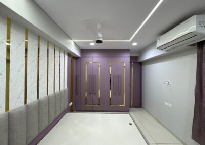 Spacious bedroom with purple laminate wardrobe, accent wall panels, and ceiling fan lighting