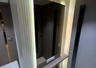 Backlit mirror niche with rounded edges, vertical wall paneling, and soft ambient lighting