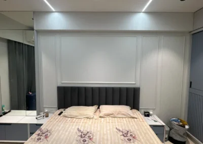 Bedroom interior with upholstered headboard, wall panel design, and POP ceiling with panel lights