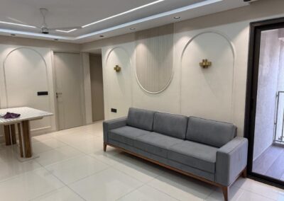 Living room seating area with custom sofa, textured wall finish, and decorative wall lighting by J Designs