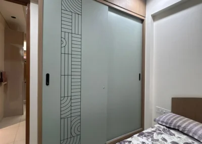 Sliding wardrobe with laminate finish, vertical CNC detailing, and floor-to-ceiling design