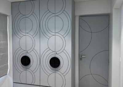 Wardrobe design with circular patterned shutters, integrated handles, and soft neutral finish by J Designs