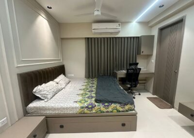 Bedroom interior with storage bed, wall paneling, POP ceiling with panel lights, and full-height curtains by J Designs