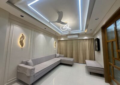 Living room interior with POP ceiling, panel lighting design, and custom sofa seating designed by J Designs