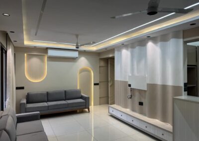 Modern living room interior with wall paneling, concealed lighting, and custom TV unit designed by J Designs