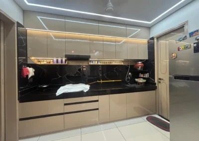 Modern modular kitchen with handle-less cabinets, black backsplash, and overhead storage by J Designs