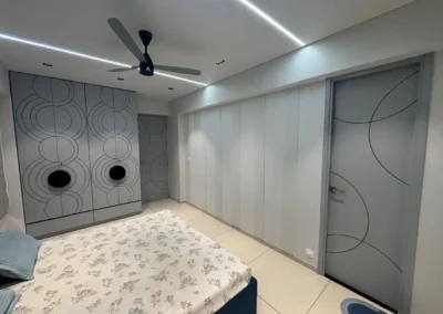 Minimal bedroom interior featuring a sliding wardrobe, neutral wall panels, and ceiling lighting